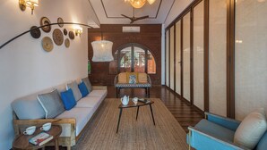 A modern interior with a sofa, armchairs, a coffee table, and decorative wall art. - Amã Stays & Trails Athaang, Dapoli (Dapoli)