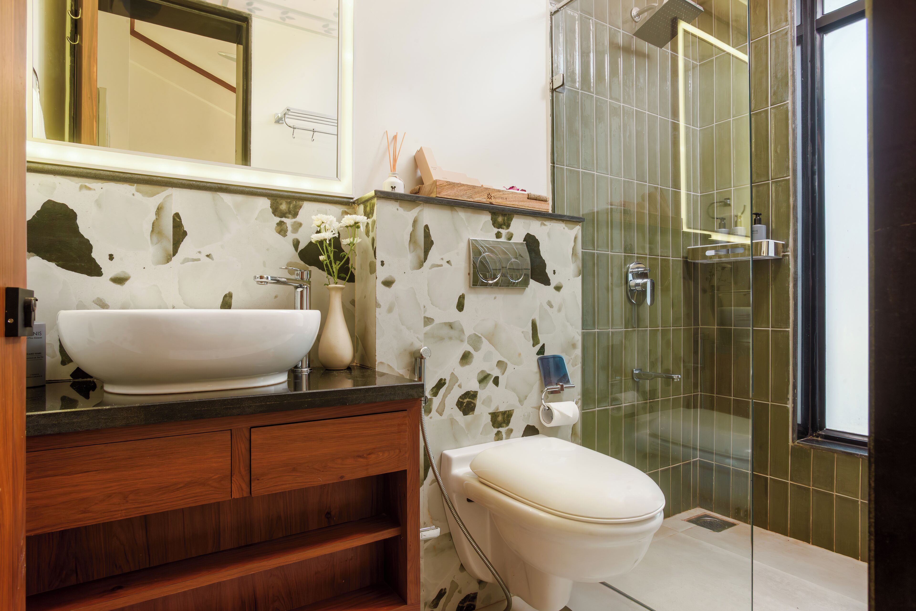 A bathroom with a large white sink, wooden vanity, a toilet, and a glass-enclosed shower area.