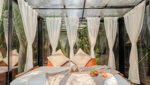 Une chambre avec un lit, des rideaux blancs et une vue sur la verdure.