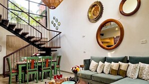 Un salon avec un escalier, un canapé, une table basse et un tapis à motifs floraux.