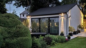 Ett modernt hus med ett glashus, omgivet av välskötta trädgårdar och en prydligt klippt gräsmatta.