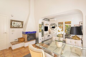 Una sala de estar con una mesa de centro de vidrio, un sofá, un televisor y una chimenea.