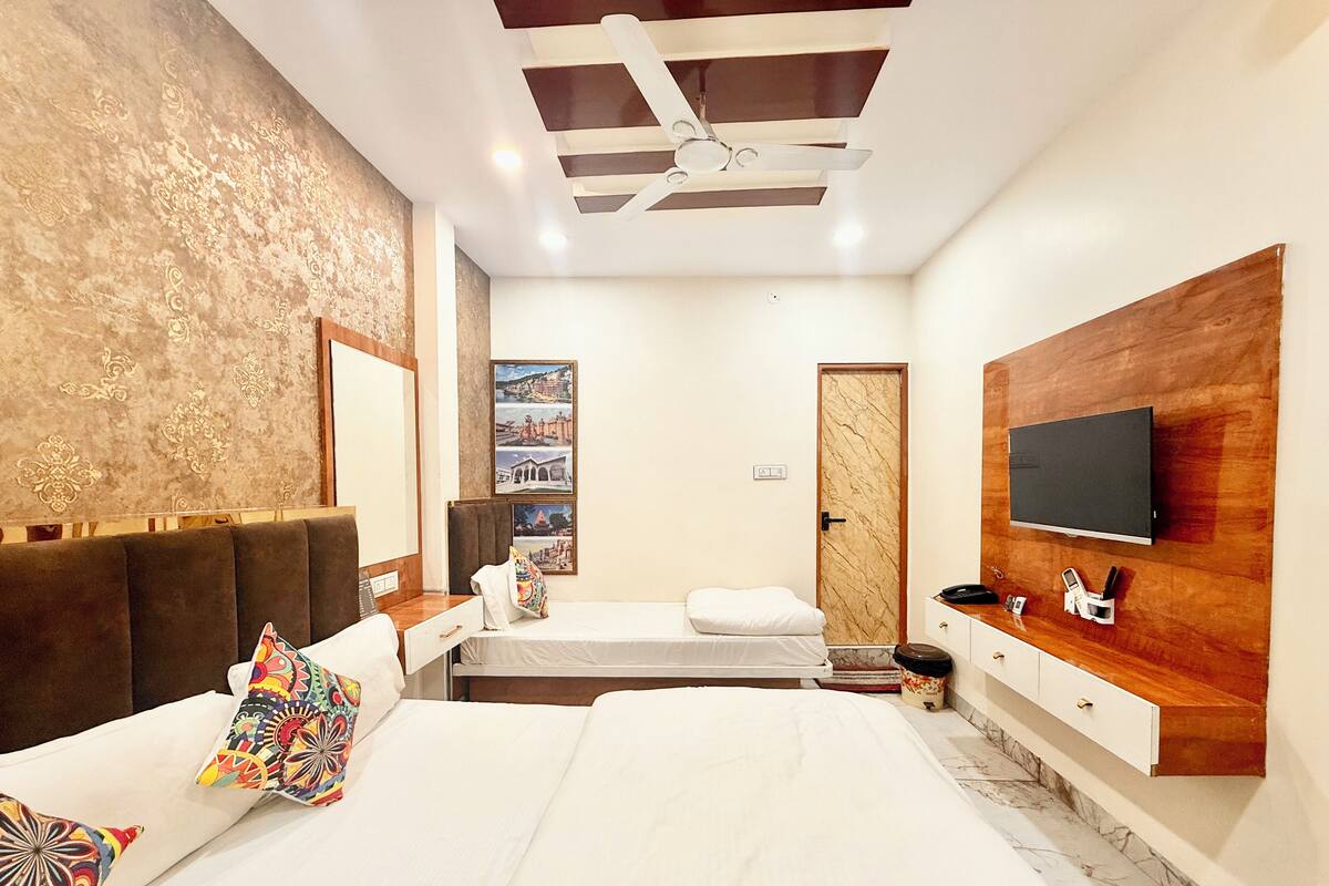 A modern bedroom with a bed, a TV, and a wooden wall.