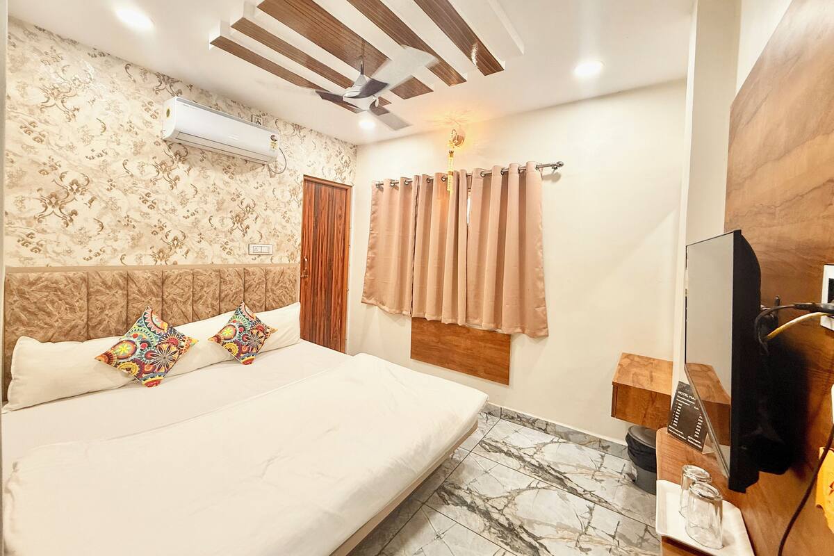 A hotel room with a bed, a ceiling fan, a TV, and a bathroom counter.