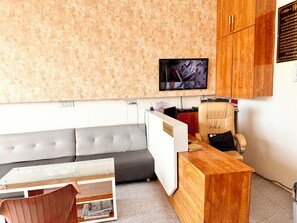 Un área de recepción con un escritorio de madera, un banco acolchado, un televisor montado en la pared y un letrero que indica la recepción.