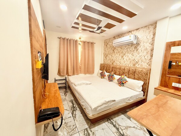 Una habitación de hotel con cama, escritorio, aire acondicionado, televisor y espejo.