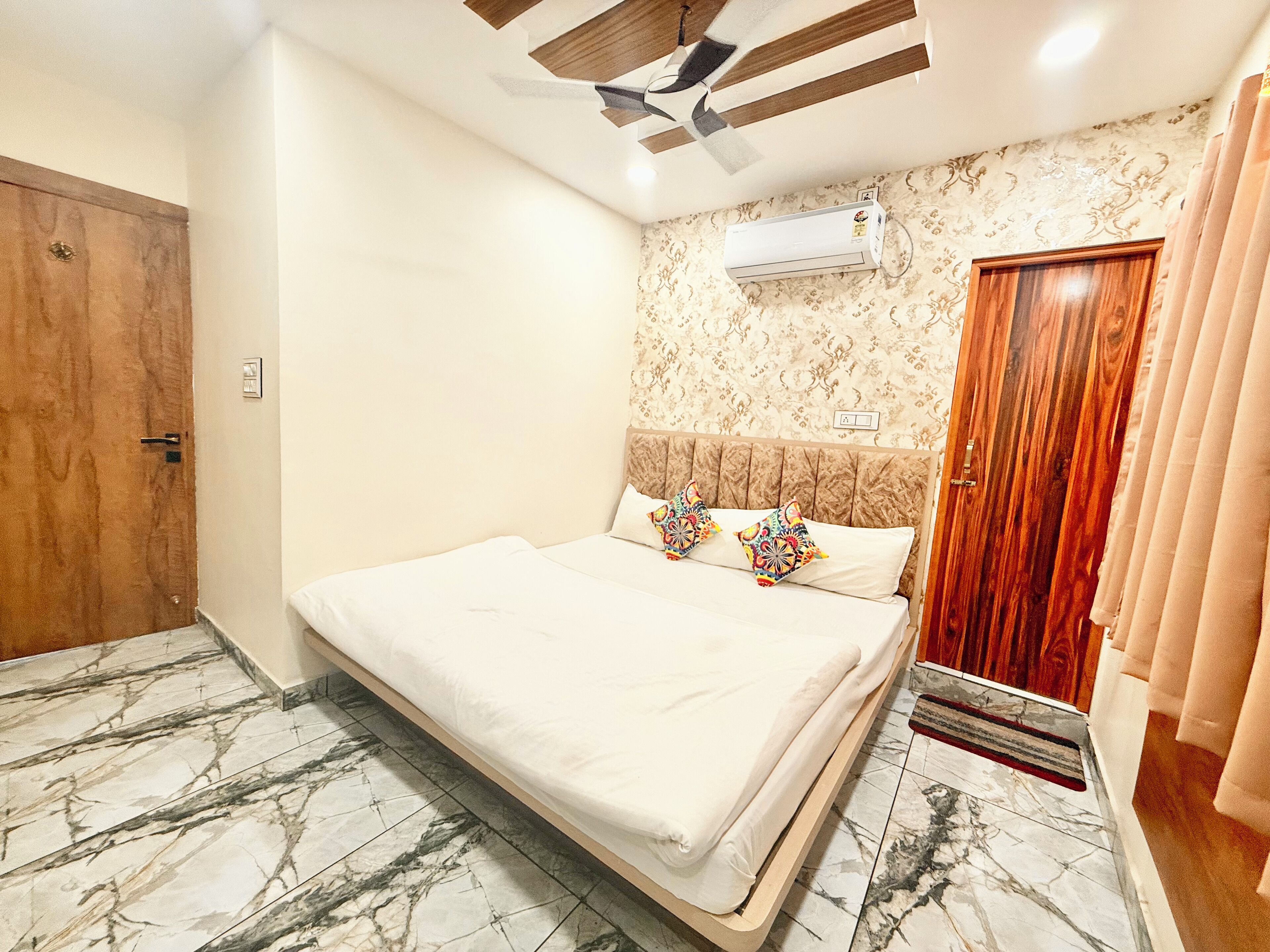 Une chambre à coucher avec un lit, une porte en bois, un appareil de climatisation et un papier peint à motifs.