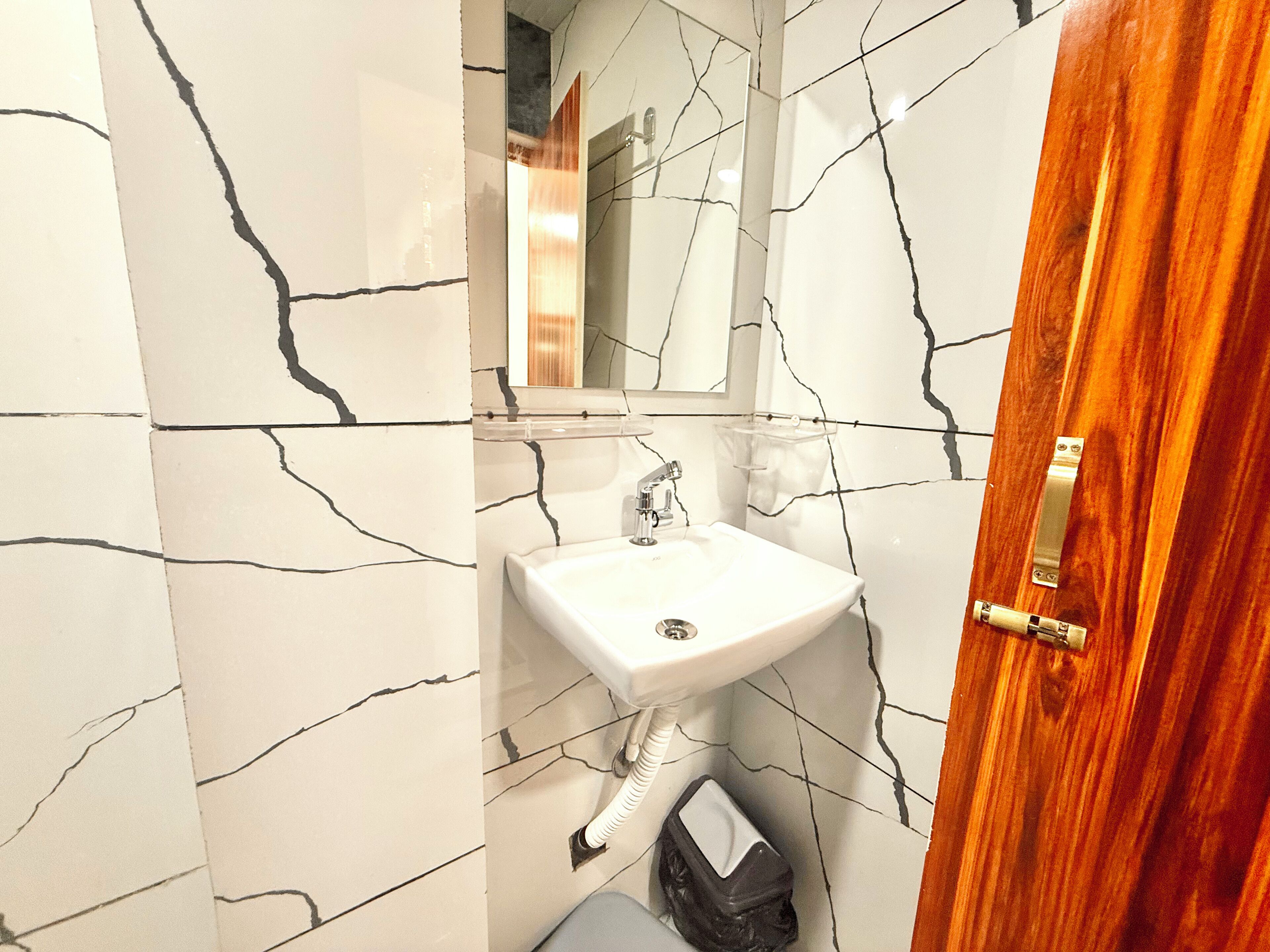 A bathroom with a white sink, a mirror, and a wooden door.