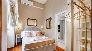 Un dormitorio ordenado con una cama grande, mesitas de noche, un armario y un espejo.