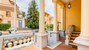 Entrada de hotel con suelo de baldosas, columnas blancas y una escalera.