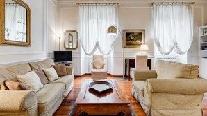 Un salón con un sofá color beige, una mesa de centro de madera, un televisor y una chimenea.