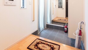 Un pasillo con piso de madera, un tapete estampado, un pasamanos, una puerta con panel de vidrio y un extintor.