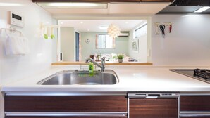 Una cocina moderna con un lavamanos de acero inoxidable, armarios de madera y lavavajillas integrado.