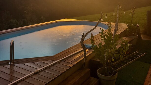 Una piscina con plataforma de madera y escalones que bajan al agua.
