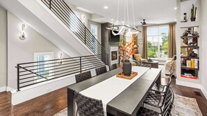 A modern living room with a staircase, a dining area, and a bookshelf. - Gated Luxury in Nashville: Rooftop Views+Fire Pit (Nashville)