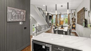 A modern kitchen with a marble countertop, a dishwasher, and a built-in oven. - Gated Luxury in Nashville: Rooftop Views+Fire Pit (Nashville)