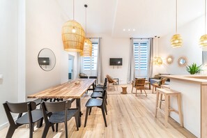 Eine moderne Küche mit einem Holztisch, schwarzen Stühlen und hängenden Rattanlampen.