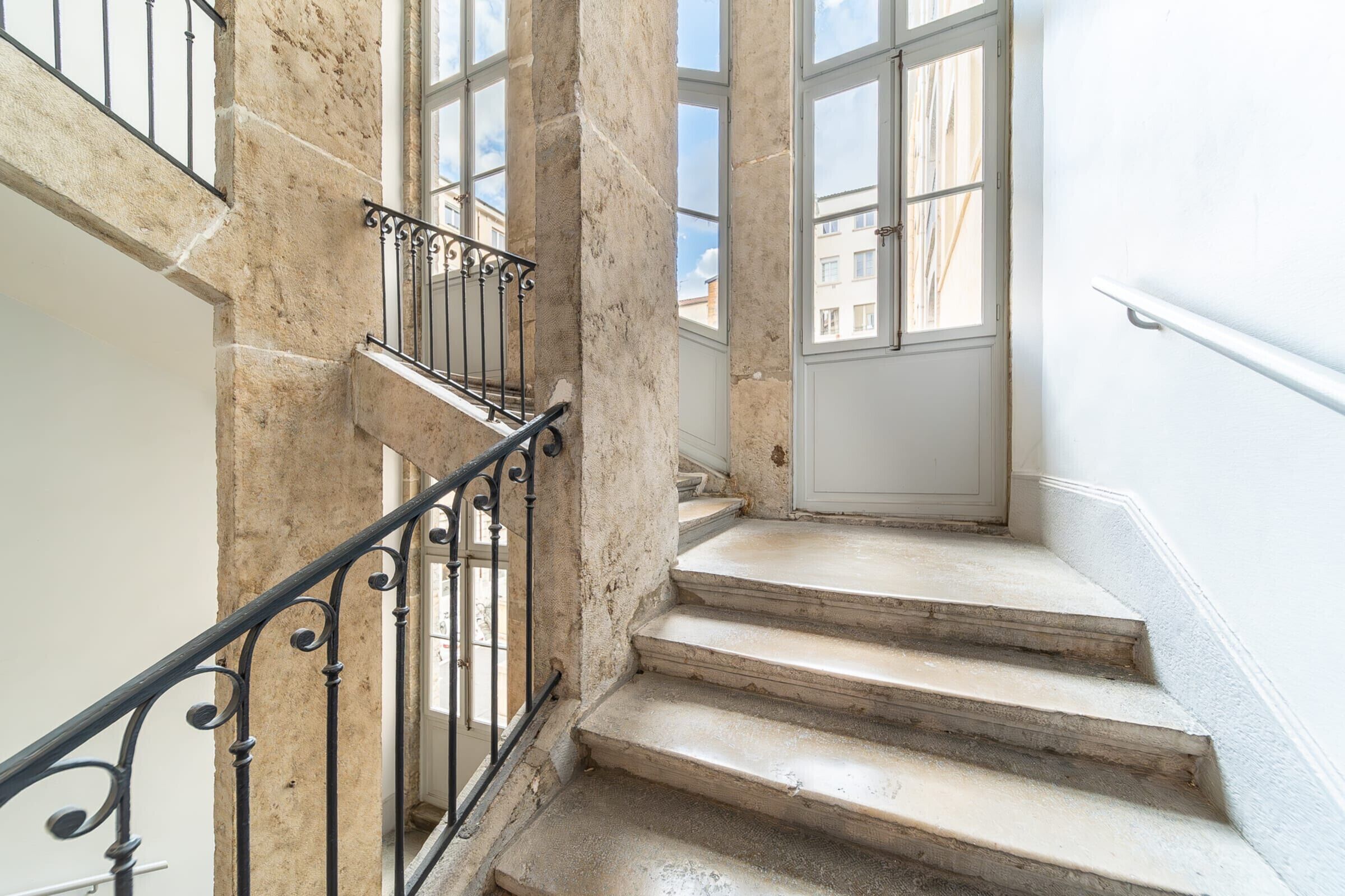 A stone staircase with metal railings leading to a door with windows.