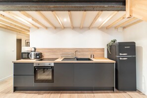 Eine moderne Küche mit Einbauofen, Spüle und einem schwarzen Kühlschrank.