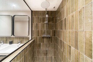 Ein Badezimmer mit Dusche, zwei Waschbecken und einem Spiegel.