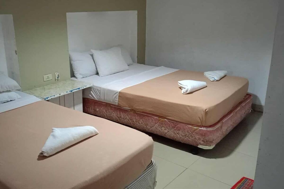 Two single beds with white linens and a small table between them.