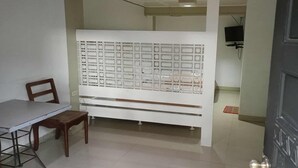 A room with a dining table, a wooden chair, a white partition with multiple compartments, and a television mounted on the wall. - T'BOLI HOTEL (General Santos)