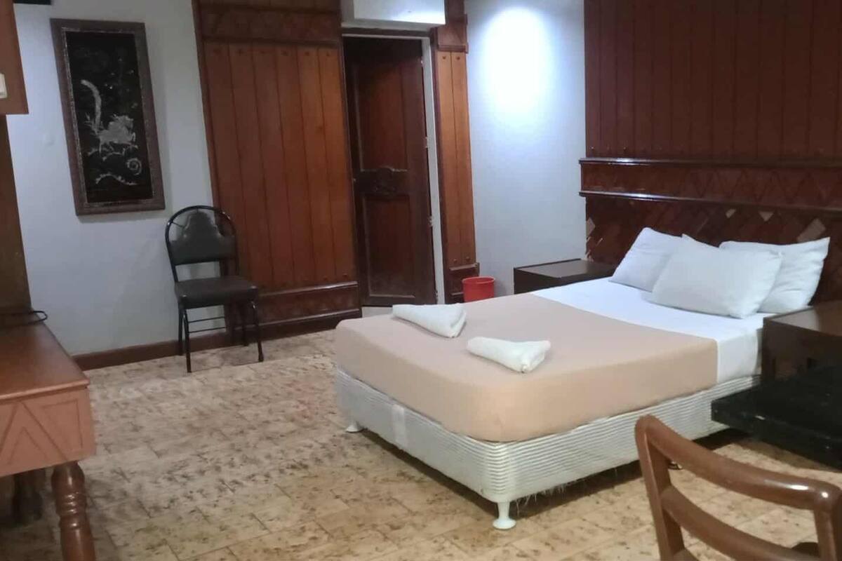 A hotel room with a bed, a desk, a chair, and a wardrobe.