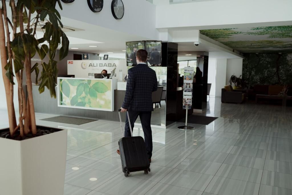 A modern lobby with a reception desk, a large potted plant, and a tiled floor.