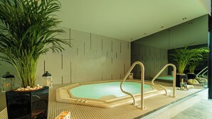 Een moderne spa met een jacuzzi, planten in potten en een betegelde vloer.