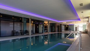 Een binnenzwembad met glazen barrière, zitgedeelte en moderne verlichting.