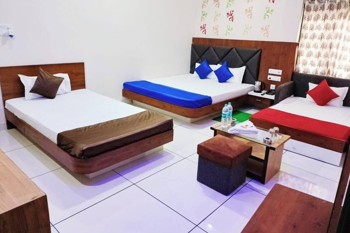 Ein Hotelzimmer mit zwei Einzelbetten, einer Schlafcouch, einem kleinen Tisch und einer Bank.