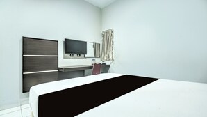 A modern hotel room with a large bed, a flat-screen TV mounted on the wall, and a desk with a chair. - OYO 94781 Hotel Lucky Inn Makassar (Makassar)