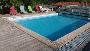 A swimming pool with a wooden deck and colorful lounge chairs. - Longère vendéenne (Saint Hilaire de riez)