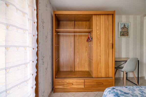Une pièce comprenant une armoire en bois, un bureau, une chaise et un lit.