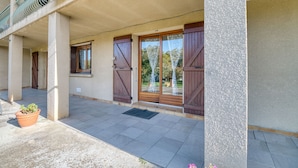 Un bâtiment doté d’un porche, de grandes portes en bois et d’une plante en pot.