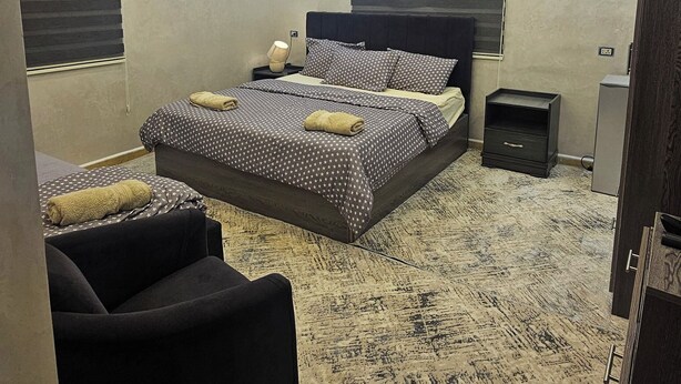 A modern bedroom with a large bed, a desk, and a chair. - hadrian's arch (Jerash)