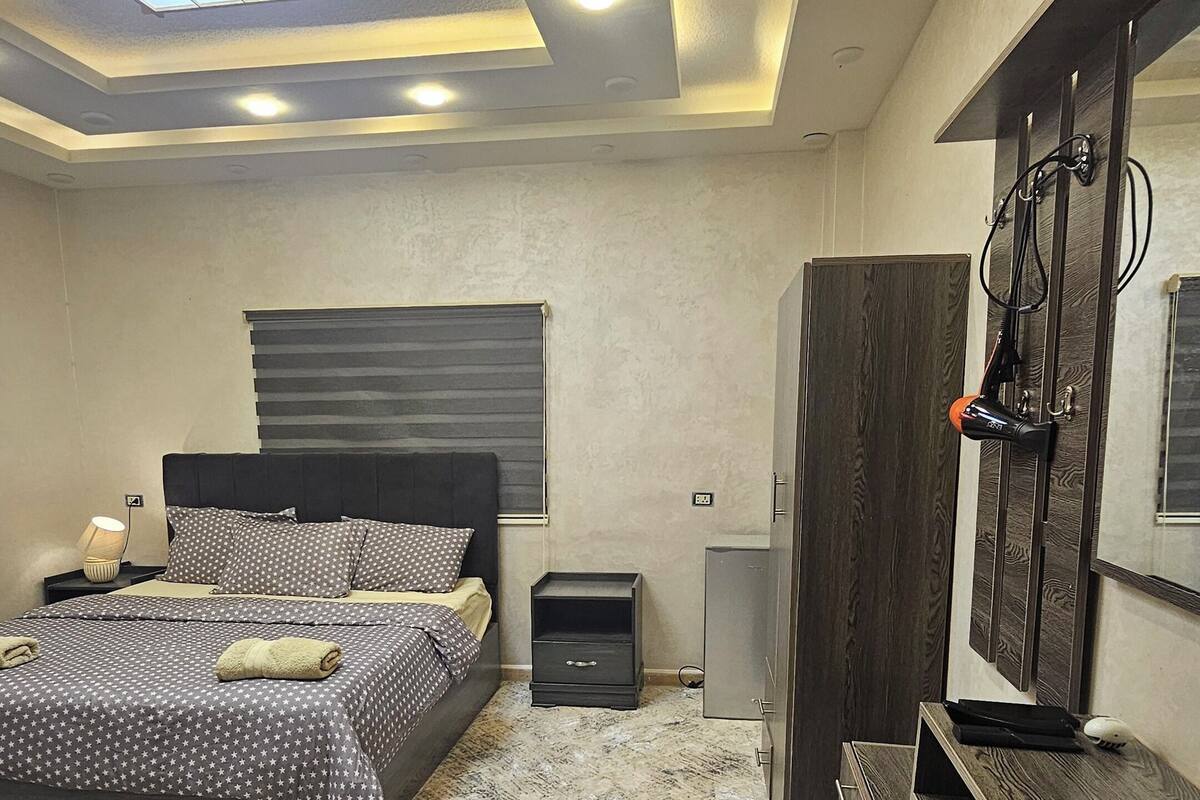 A modern bedroom with a bed, a TV, a wardrobe, and a desk.