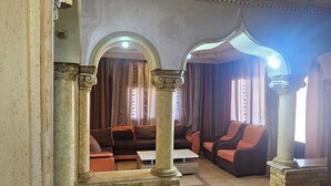 A spacious lobby with a high ceiling, ornate columns, and a seating area with sofas and armchairs. - hadrian's arch (Jerash)