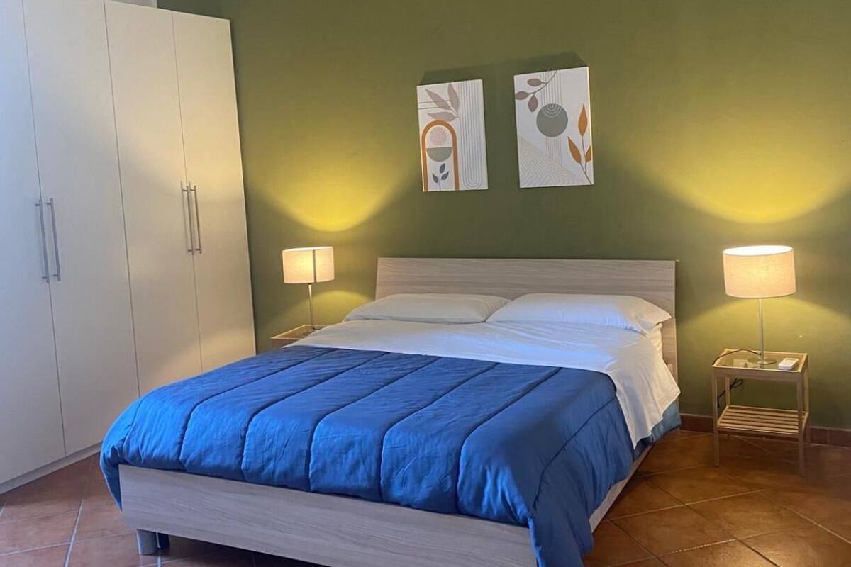 Un dormitorio con una cama, dos lámparas de noche, un armario y dos obras de arte en la pared.