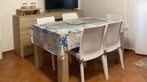 A dining area with a table, chairs, a television, and artwork on the wall. - SAMPOLO70 APARTMENTS (Palermo)
