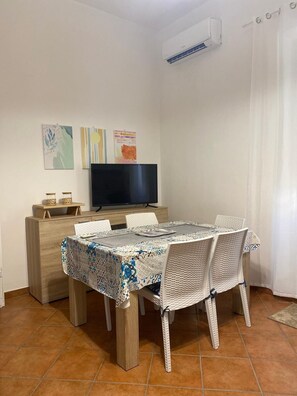 Un comedor con una mesa, sillas, un televisor y obras de arte en la pared.