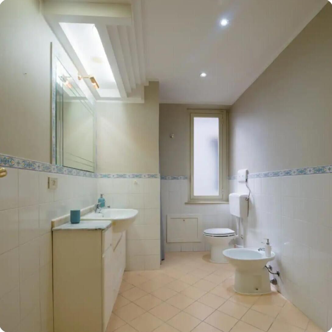 A bathroom with two sinks, a toilet, and a window.