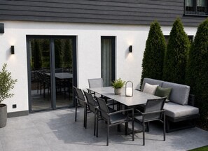 A patio with a table and chairs, a sofa, and a potted plant.