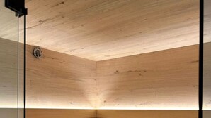 Un sauna avec des bancs en bois et un récipient noir sur l’étagère inférieure.