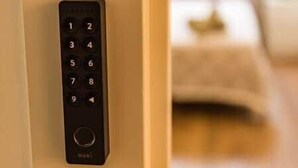 Seinään asennettu elektroninen näppäimistö, todennäköisesti huoneen lukitsemiseen tai turvallisuuden lisäämiseen.