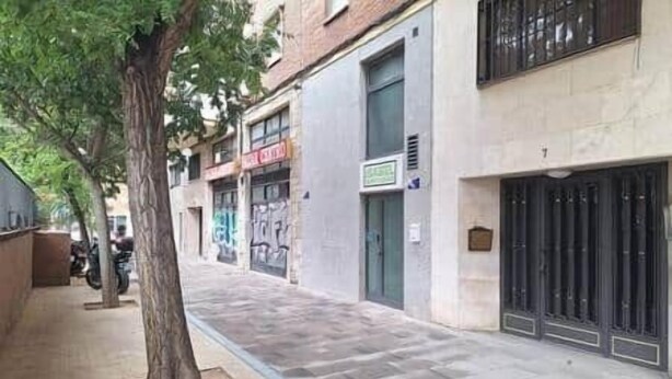 A street view with buildings, a tree, and a closed shop with a sign. - Isabel Guest House Room 2 (Madrid)