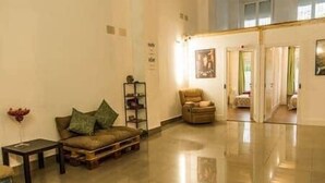 A spacious lobby with a leather sofa, a small table, and a bookshelf. - Isabel Guest House Room 2 (Madrid)