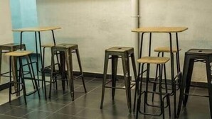 A row of bar stools with attached tables in a room with tiled flooring and a plain wall. - Isabel Guest House Room 2 (Madrid)