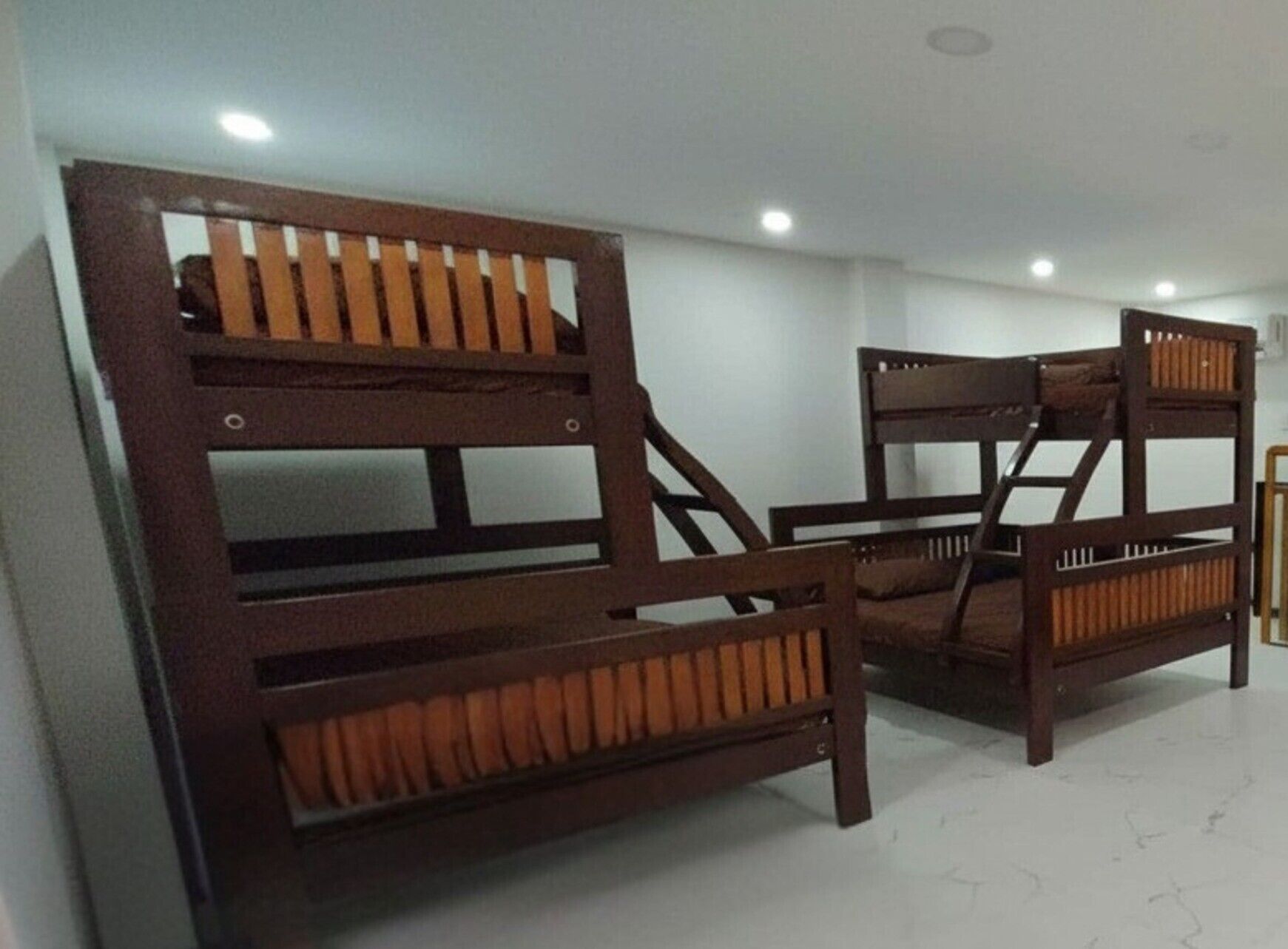 A room with two wooden bunk beds and a chair.
