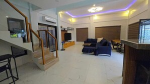 A spacious living area with a sofa set, a TV, and a staircase leading to another level. - SC RESORT (Concepcion)